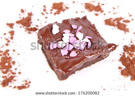 Slice of a brownie covered with chocolate and decorated with sugar hearts