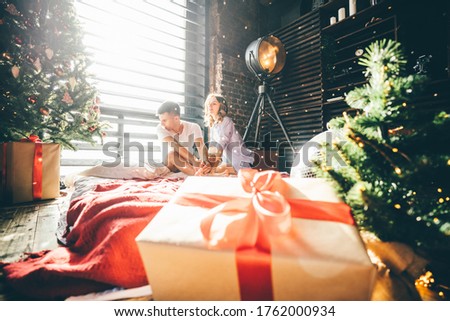 Couple celebrating date in modern room. Christmas, new Year or birthday concept. Beautiful gift box and blurred couple on background. Copy space for text.
