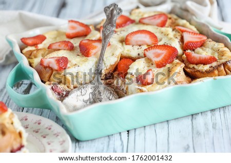 Strawberry cheesecake French toast casserole with missing piece. Made with cream cheese and strawberries. Selective focus with blurred background.