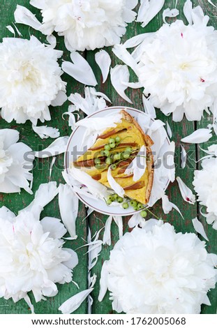 
A beautiful piece of cake on a wooden table among white peonies.