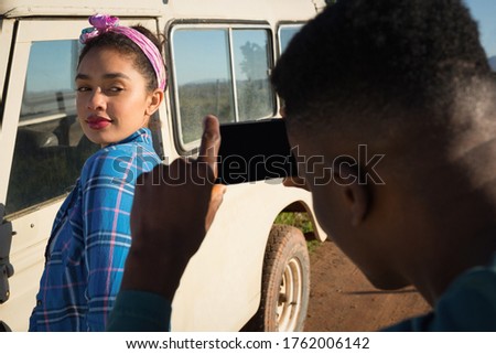 Man clicking picture of woman with mobile phone at countryside