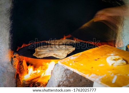 Hand making gozleme bread on wooden fire with motion blur in rural  region in Turkey