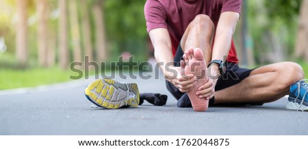Young adult male with his muscle pain during running. runner man having leg ache due to Plantar fasciitis. Sports injuries and medical concept Royalty-Free Stock Photo #1762044875