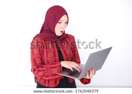 Young Asian Islam woman is shock when holding and working on laptop computer isolated white background
