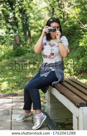 Woman taking photo at park outdoor with copy space. Beautiful woman tourist photographer with vintage camera. lady photographer, female Portrait.
