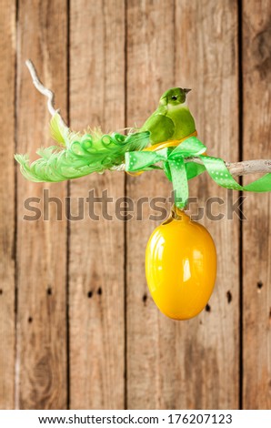 Easter or spring vintage wood background - green bird and yellow egg on a twig. Decorative layout with free text space good for seasonal poster.