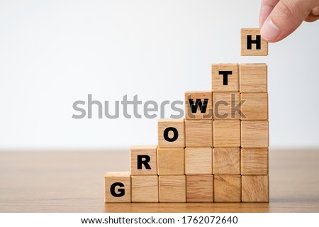 Hand putting wooden cubes block which print screen growth wording . Target of investment and business growth concept.