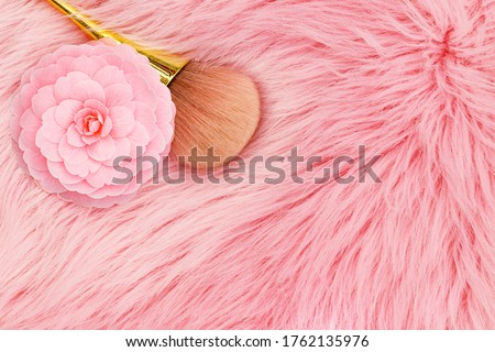 Pink Camellia flower and make up brush on fur trendy background. Professional Makeup Brush on pink fur fabric, close up 