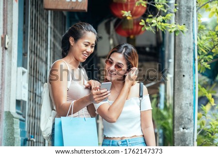 Portrait of two happy friends laughing and looking a smart phone stock photo