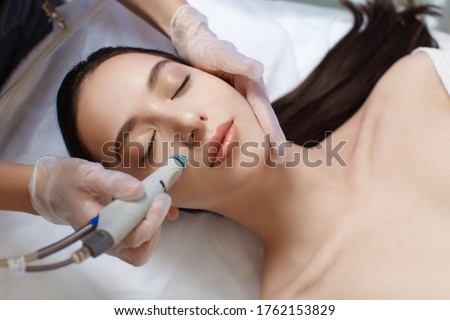 Professional female cosmetologist doing hydrafacial procedure in Cosmetology clinic. Royalty-Free Stock Photo #1762153829