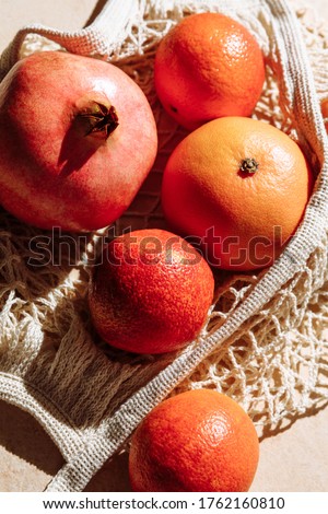 Fresh fruits in eco friendly mesh shopping bag. Trendy shadows and sunlight. Zero waste concept, flat lay on beige background, copy space, top view