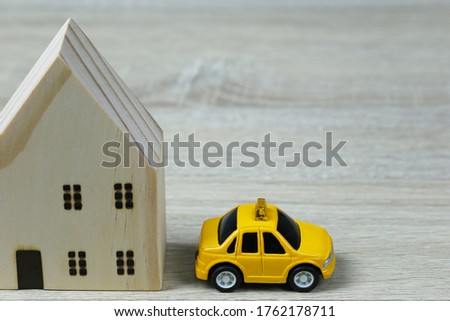 Toy cars and wooden houses in concept of buying housing and insurance or Travel concept.