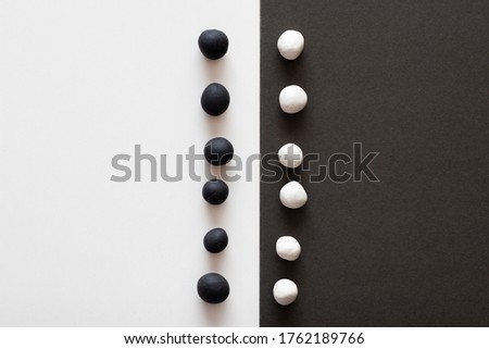 Black and white plasticine balls on contrasting sides of background. Concepts of racism and division, contrast in colors representing difference ideologies and thoughts