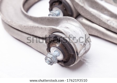 Close-up of the silent block on the used aluminum suspension arm on a white isolated background in a photo studio, spare parts for sale at an auto-parsing or for replacement when servicing a car.