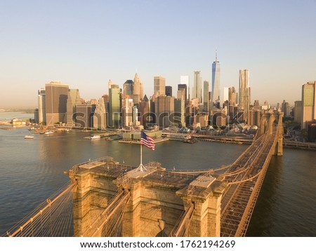 Brookyln Bridge Aerial view with American Flag waving and Manhattan Skyline in the background in Daylight