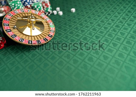 Roulette wheel, stacks of poker chips, dice, green canvas with cards signs. Casino and gambling concept.