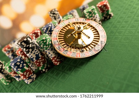 Roulette wheel, stacks of poker chips, dice, green canvas with cards signs. Casino and gambling concept.