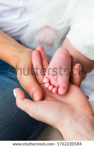 
Parents hold in the palm of their hand the newborn’s leg.