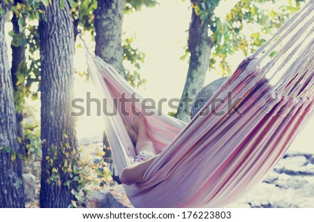Person relaxing in a hammock in the shade of a tree on a hot summer day, view from behind. With retro filter effect. Royalty-Free Stock Photo #176223803