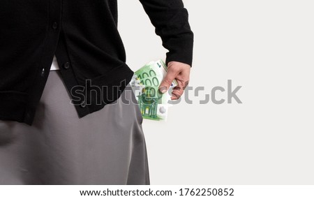 Woman's hand gets money from pockets in her clothes. The female hands holds euro.