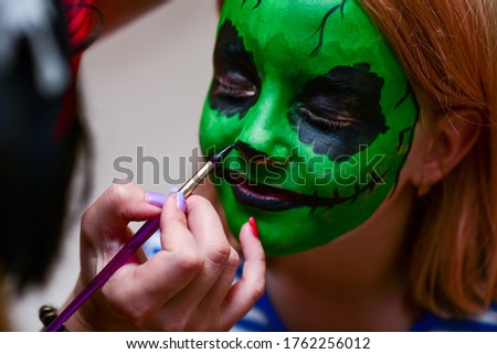 The animator draws green colors on the face of a child.