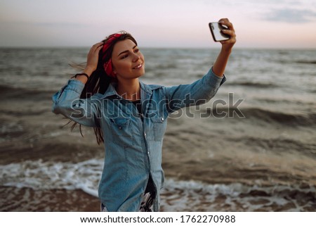 Beautiful girl takes a selfie on the beach at sunset. The concept of relax, travel and summer vacation.