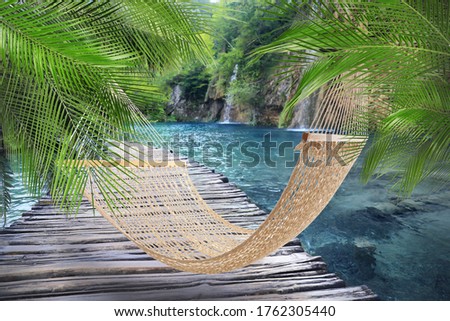 Hammock near wooden bridge and waterfall on sunny day 