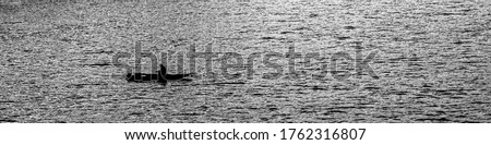 Fisherman sitting in the boat fishing in mindfulness concentration and silence, alone in the open space of water surface