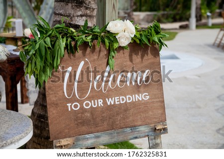 Wooden welcome table board sign at the wedding on the beach with welcoming romantic words during destination wedding marriage ceremony, invitation for the guests