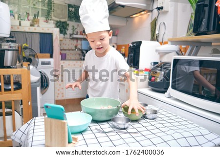 Cute happy smiling Asian little kindergarten boy having fun cooking breakfast and recording a video for his followers, Young blogger make vlog for social media channel, photo in real life interior