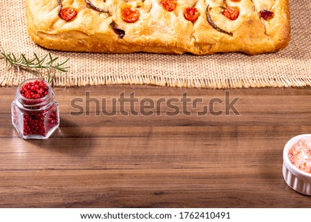 Italian focaccia bread with rosemary, cherry tomatoes, olive, peppercorns and pink himalayan salt