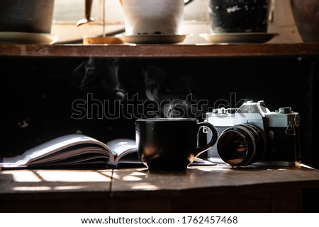 morning light refreshing black cup of hot coffee and stream with silver vintage camera and white page writing diary on wood table focus on camera stock photo