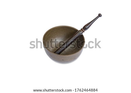 A golden Tibetan bowl with a metal stick sitting isolated on white background.