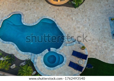 A 4k high resolution aerial view of a pool and spa with a travertine patio and outdoor fireplace. Royalty-Free Stock Photo #1762493540