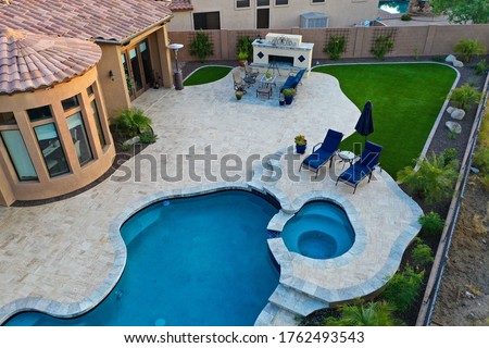 A 4k high resolution aerial view of a pool and spa with a travertine patio and outdoor fireplace. Royalty-Free Stock Photo #1762493543