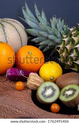 A picture of some delicious fruits in a frame. Honeydew melon, pineapple, some kiwifruits, oranges, lemons and some Chinese lantern fruits.