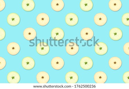 Pattern of red and green apple slices on light blue background