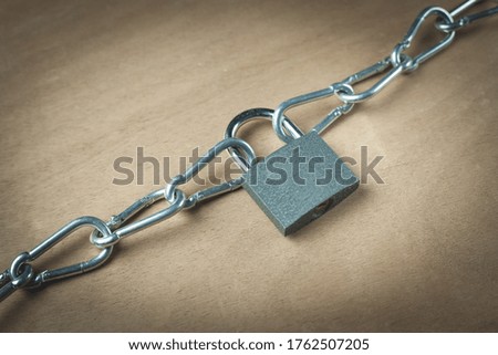 Padlock with a steel chain on a wooden background. 