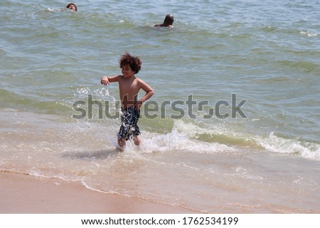 Child playing with the waves at the beach having fun in the ocean on a clear summer day