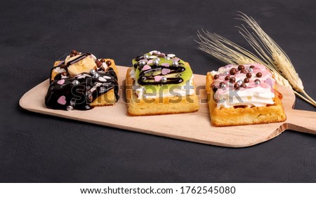 Delicious waffles with cream and fruit on a black background and presentation board - Image