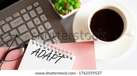 Office supplies, devices, coffee cup and glasses on white table with text ADAPT