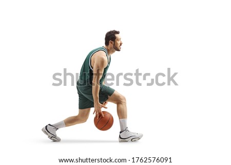 Full length profile shot of a professional basketball player leading a ball between his legs isolated on white background