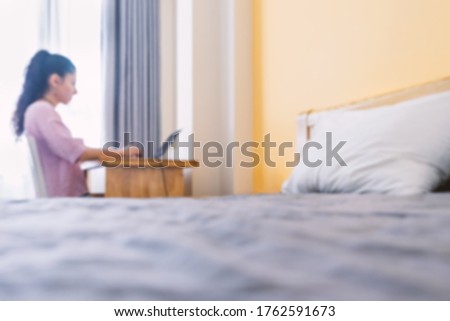 Blurred photo Woman working on a laptop from home or hotel. Workplace in a small apartment. Always in touch. Work from home concept.