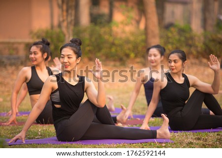 Asian Beautiful Women Group Doing yoga by the lake in the morning with warm sunshine
