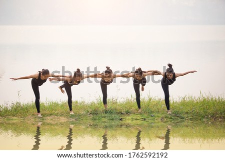 Asian Beautiful Women Group Doing yoga by the lake in the morning with warm sunshine