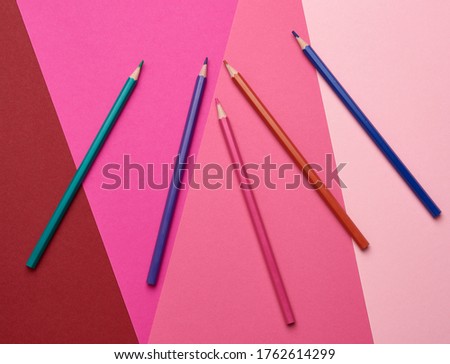 sharpened colored wooden pencils on an abstract background of cardboard, top view, place for an inscription