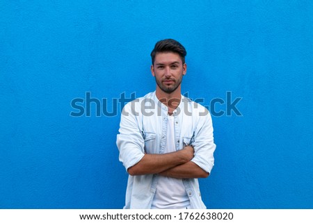 man posing outdoors on a blue background - portrait of man looking on camera with blue background
