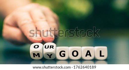 Hand turns dice and changes the expression "my goal" to "our goal". Royalty-Free Stock Photo #1762640189