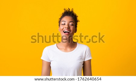 Positive Emotions. Cheerful black girl laughing with closed eyes, isolated over yellow studio wall, banner