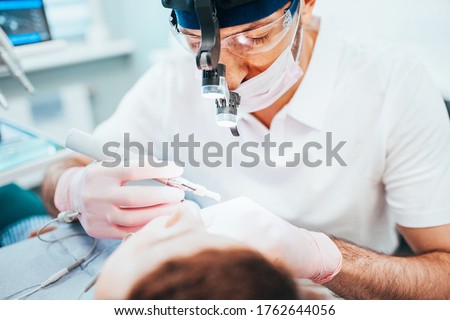 Dentist cleans tooth canals of patient and removes nerve - pulpitis treatment Royalty-Free Stock Photo #1762644056